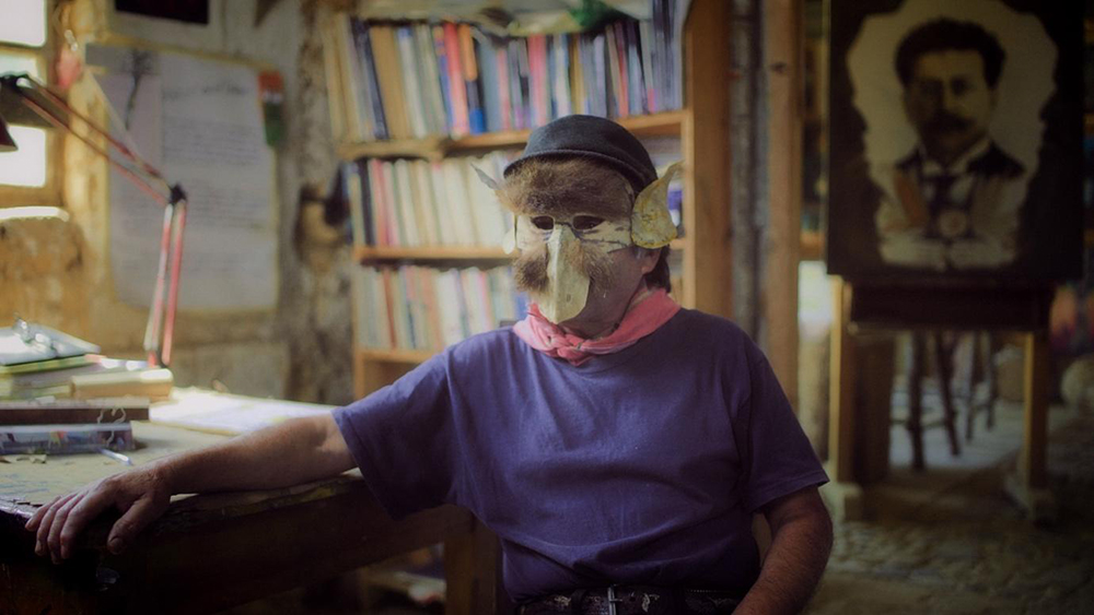 Figure 2: Still from El Edén Subvertido (The Subverted Eden). Also wearing a mask, one of  the interviewees of the film, an artist and  narrator on the importance and legacy of Ricardo Flores Magón.